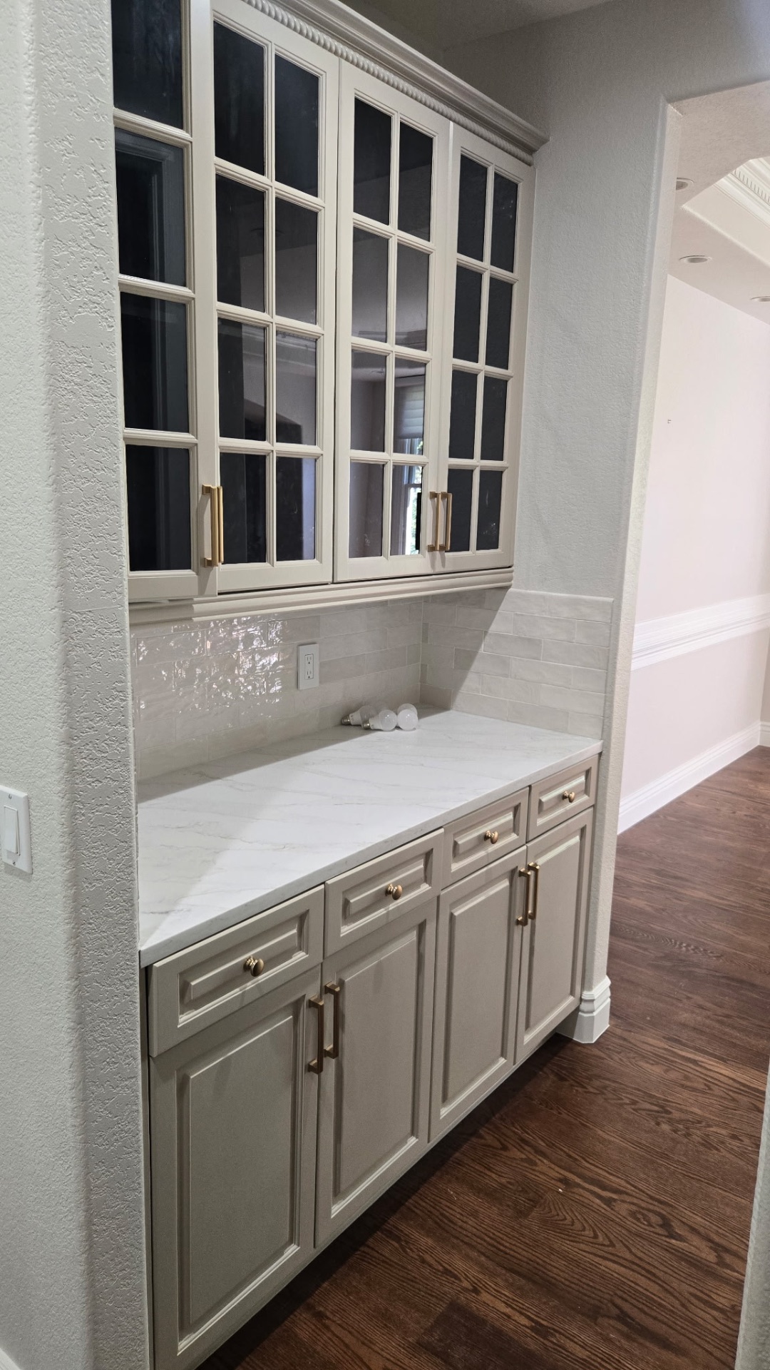 Built-in butler's pantry with glass-front cabinets and marble counter