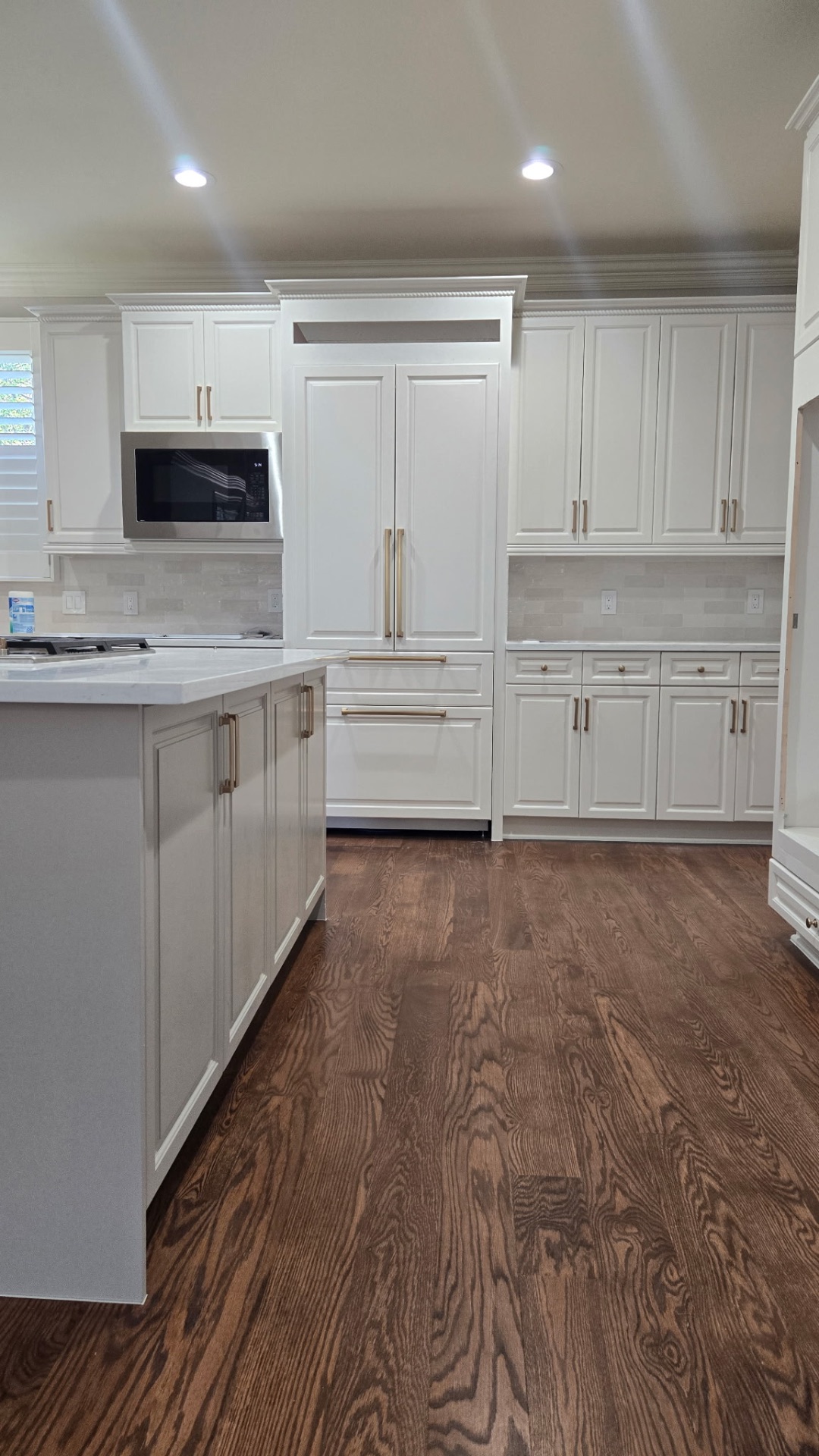 Custom white cabinetry with brass hardware and tile backsplash