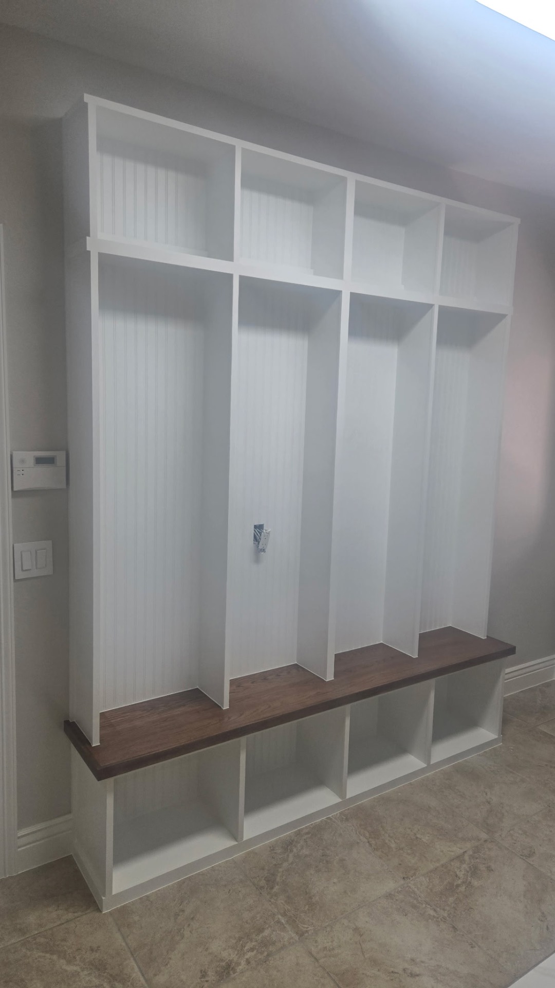 Custom mudroom built-in with beadboard lockers and stained bench