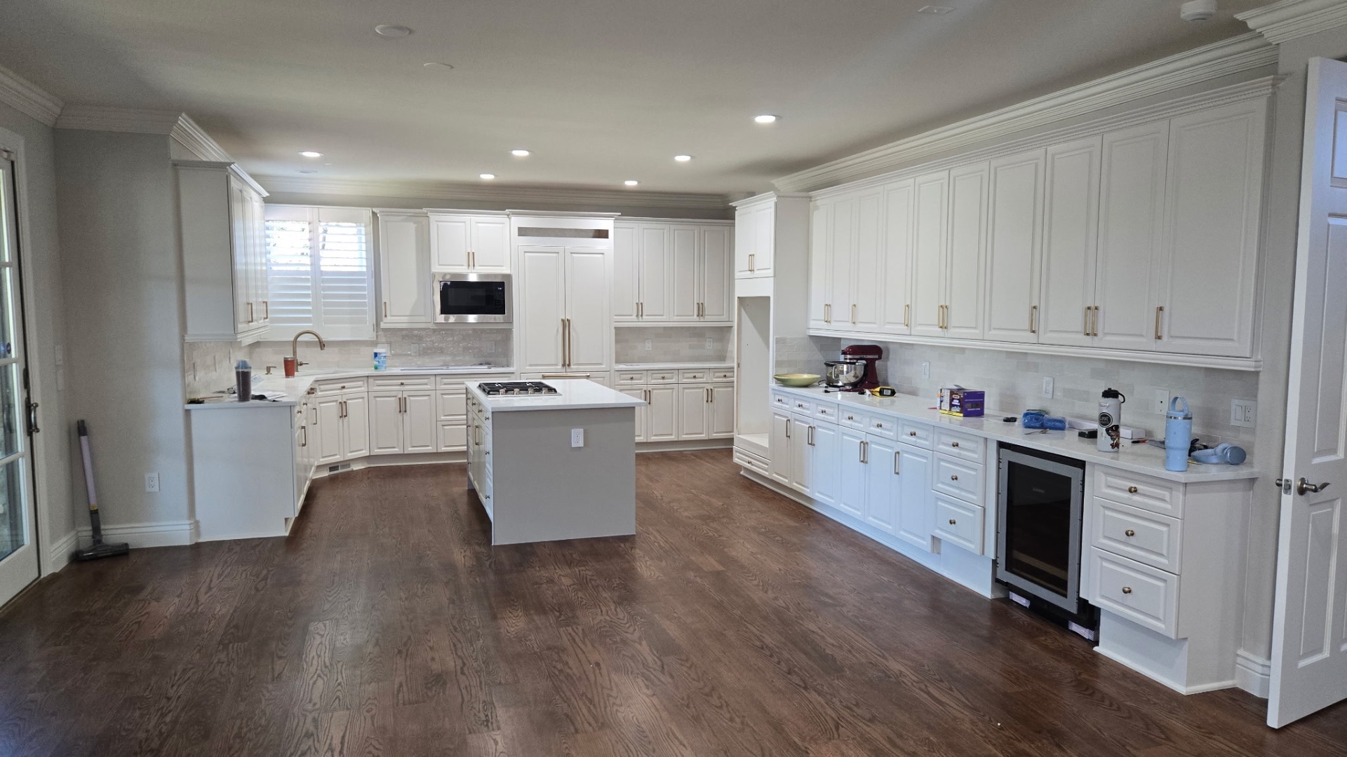 Full white kitchen remodel with island, custom cabinetry and hardwood floors
