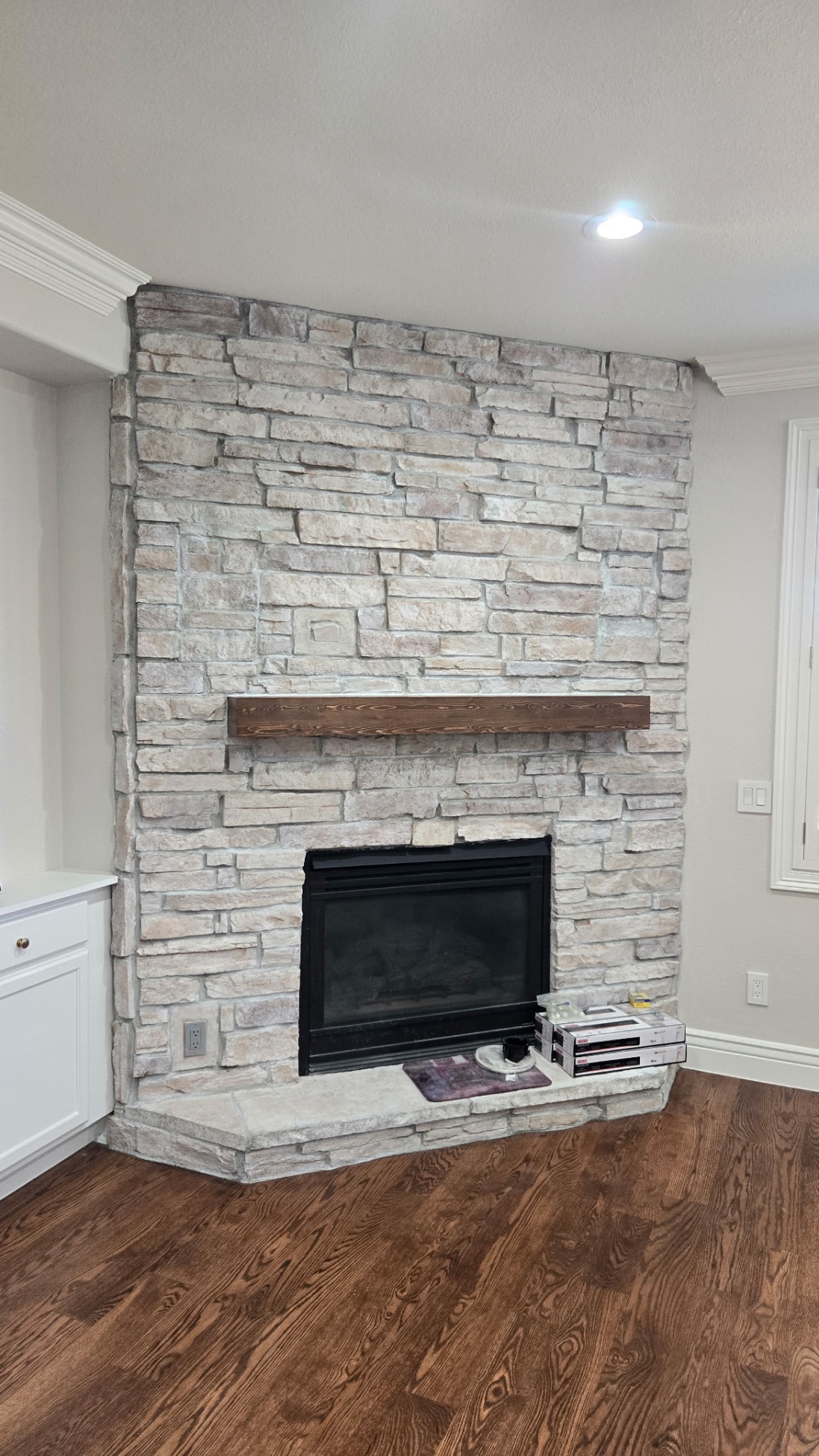 Stacked stone fireplace with stained wood mantel